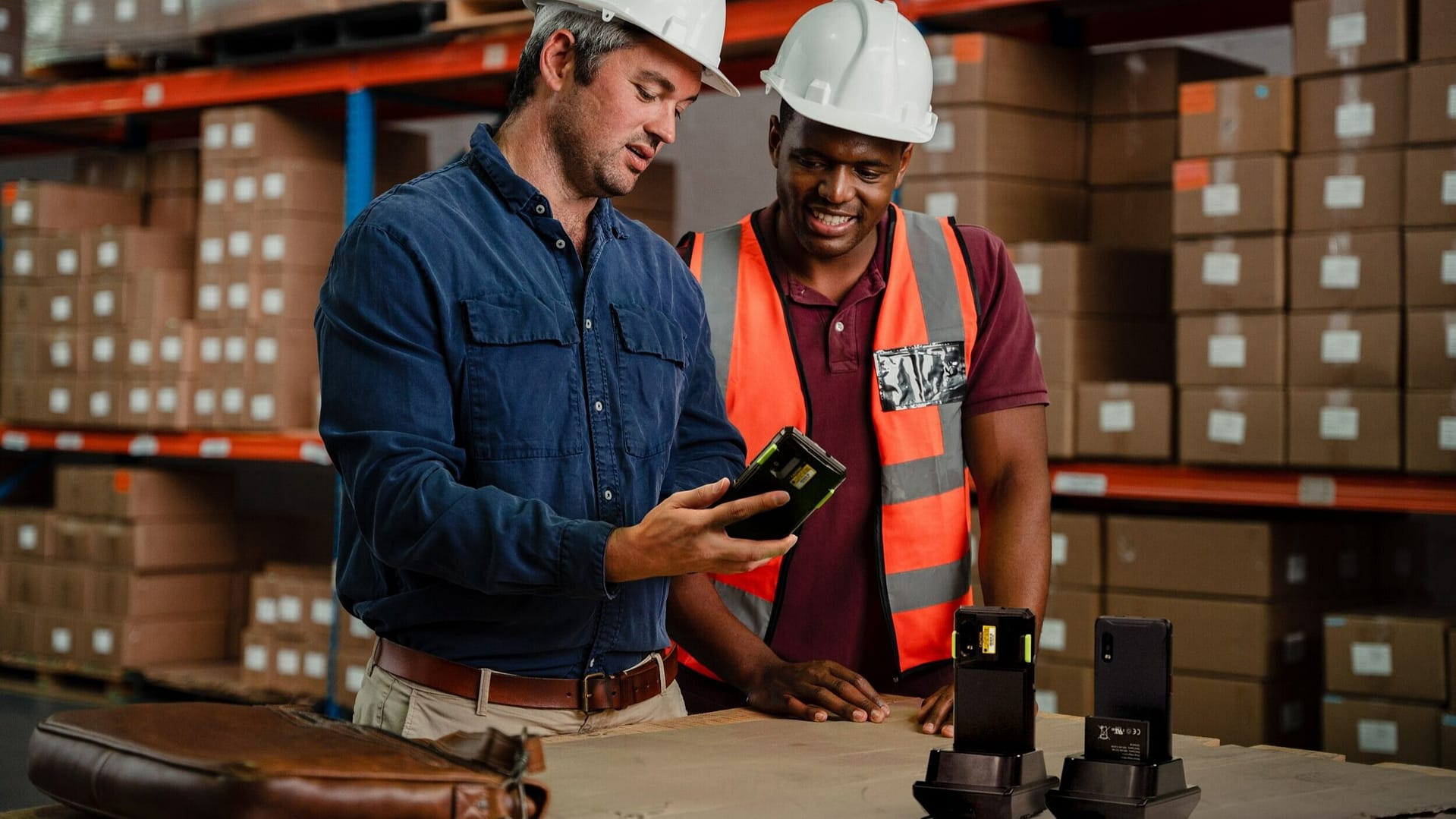 Two workers in a warehouse looking at a mobile computer