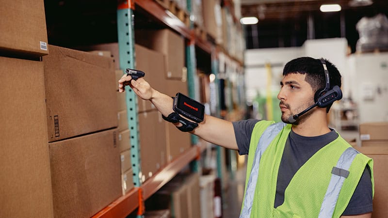 A warehouse worker using a mobile scanner in a warehouse